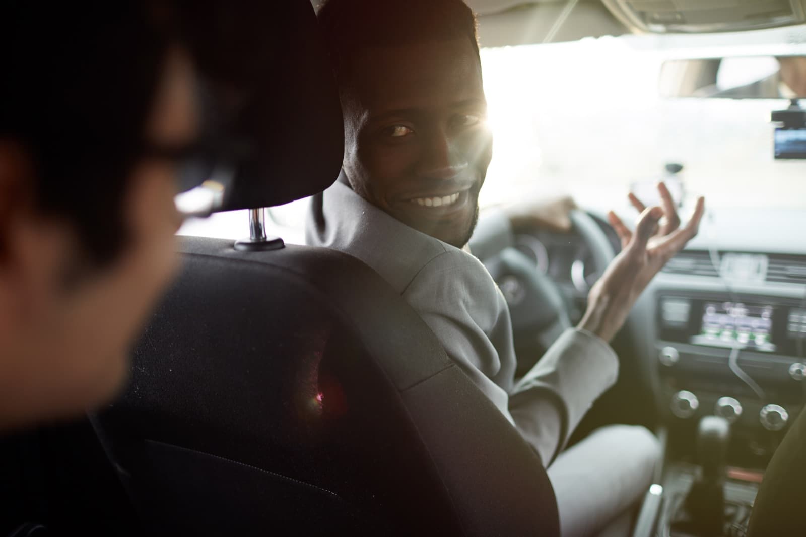 Un chauffeur se retourne en souriant vers son passager pendant un échange chaleureux